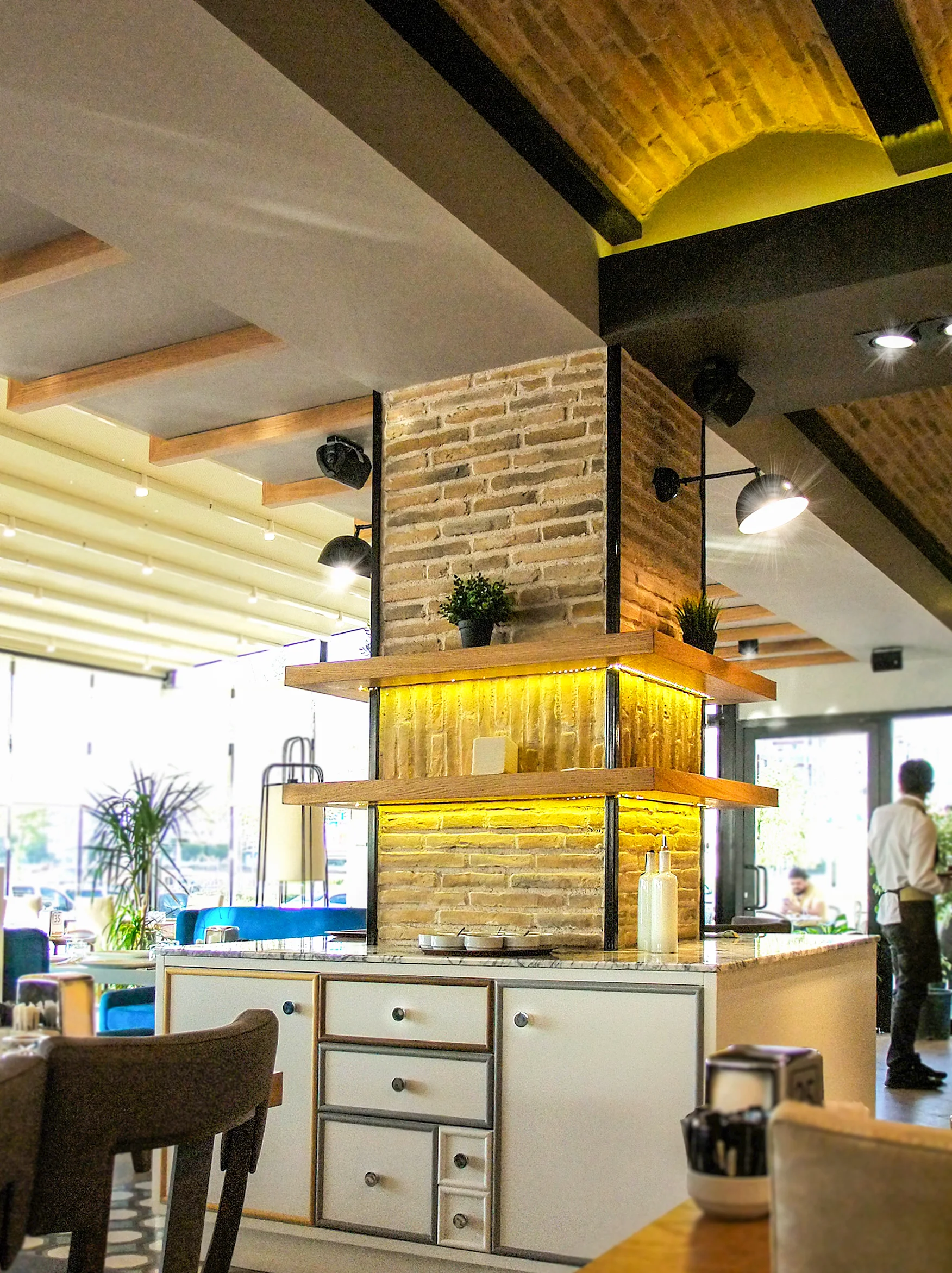 Fırın-ci 75 İlk Konsept restoranında ahşap masa düzeni, gri sandalyeler, tuğla duvar ve modern iç mekân tasarımı.