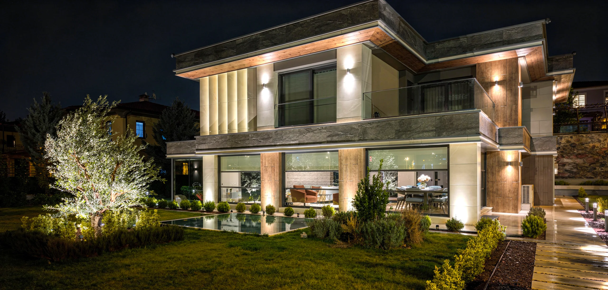 Geometrik hatlara sahip modern villa dış cephesi, gün ışığını yansıtan geniş camlar ve taş kaplama uyumu, NDO Mimarlık Diyarbakır villa projesi
