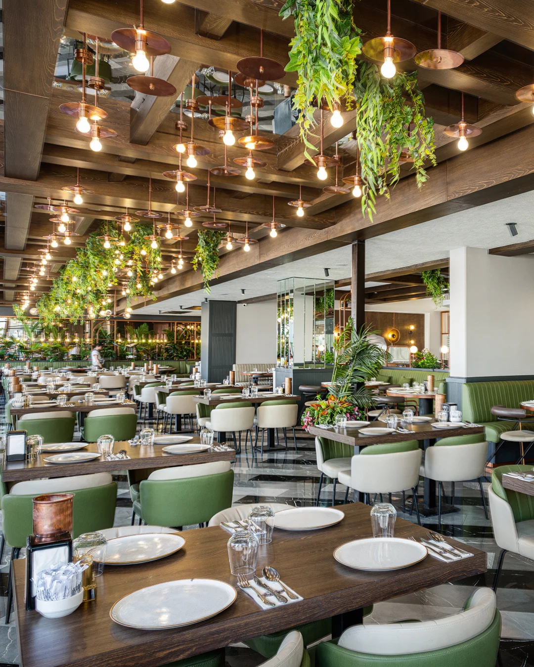 Geniş pencerelerden doğal ışık alan restoran locaları, bej kapitone oturma grupları ve yeşil bitkilerle zenginleştirilmiş ahşap tavan, NDO Mimarlık