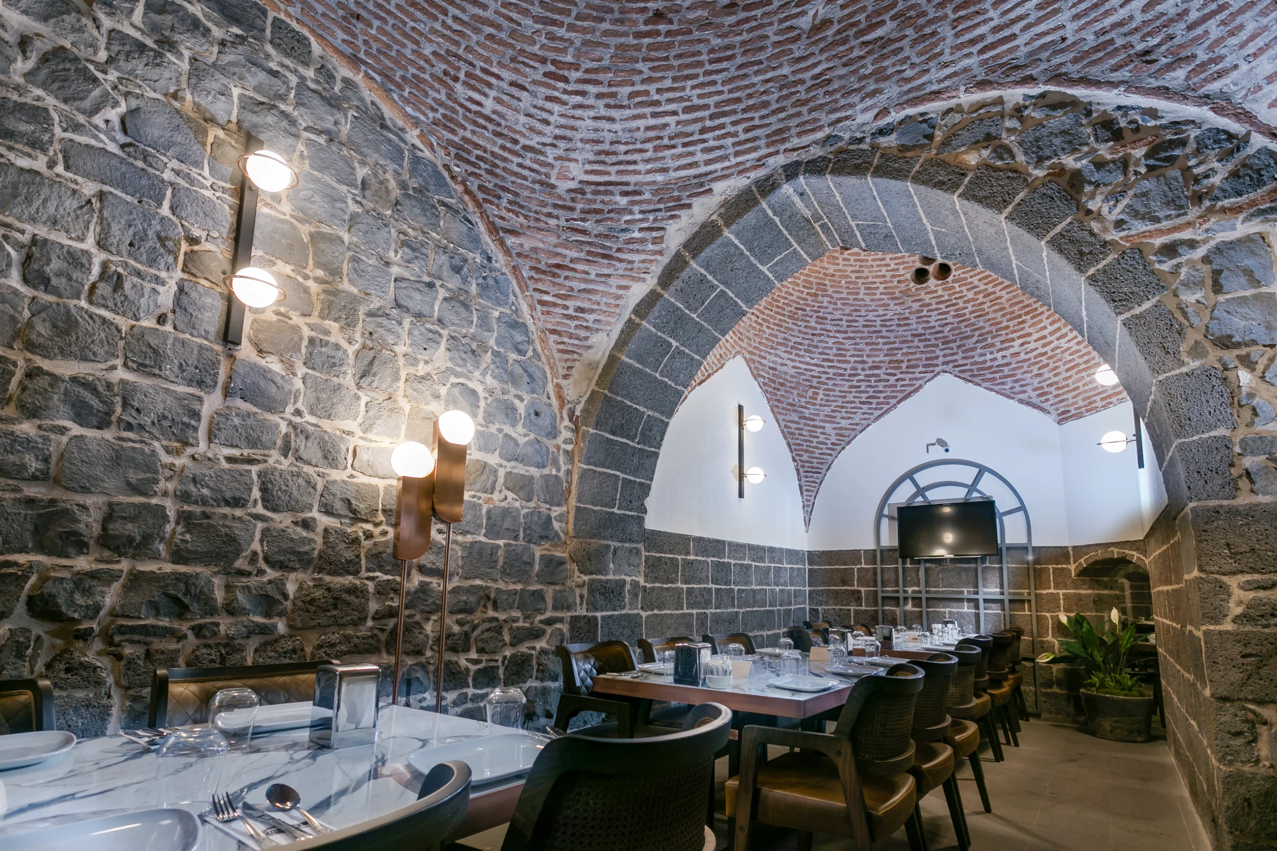 Fırın-ci Sur restoranında Tarihi Vahap Ağa Hamamı’nın taş ve tuğla dokusunu öne çıkaran iç mekân tasarımı.