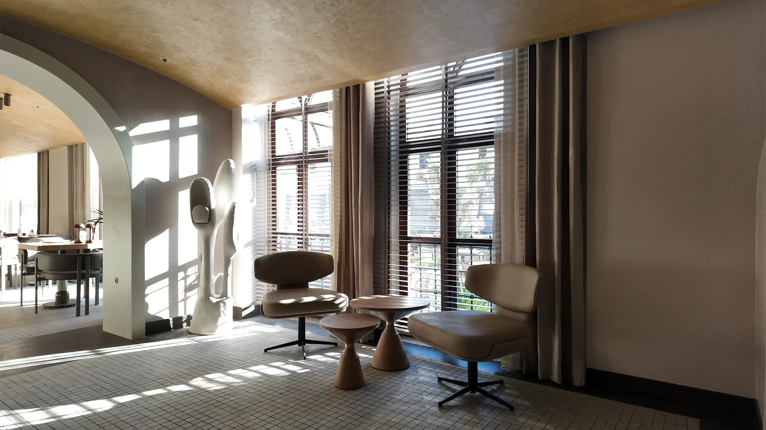 Rempart Hotel bekleme alanında geniş kemerli açıklık, yumuşak oturma elemanları, büyük saksı bitkileri ve lineer gizli ışıklarla oluşturulan sakin lobi atmosferi, NDO Mimarlık
