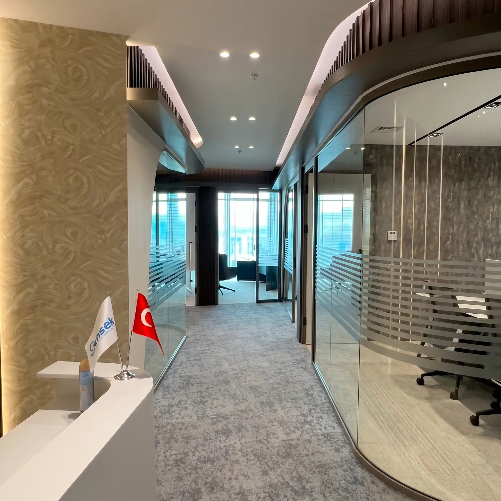 Kavisli cam toplantı odası cephesi, koyu ahşap latalı üst bant ve gizli ışık detaylarıyla tasarlanan Mahall Ankara ofis iç mekânı, NDO Mimarlık