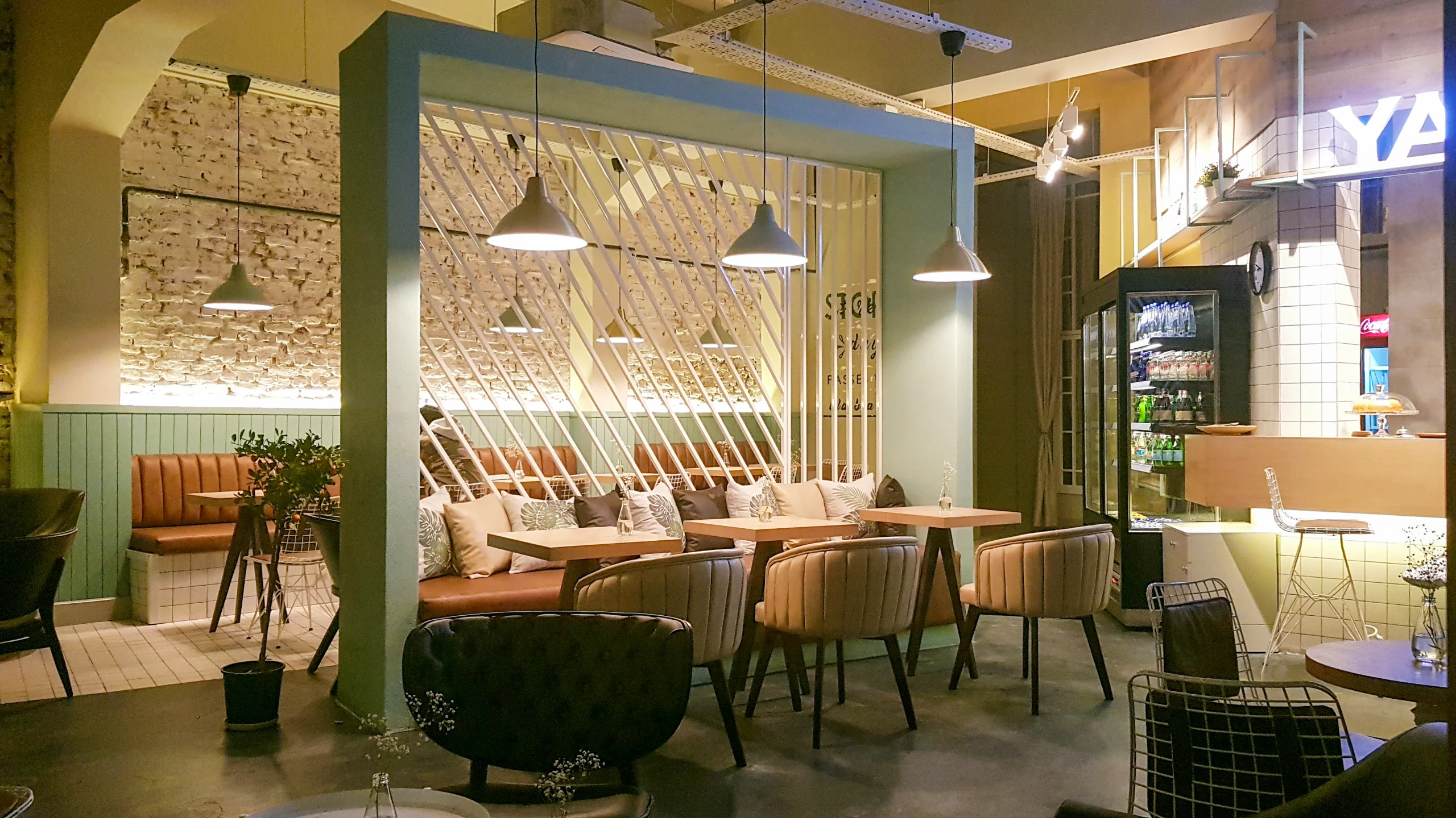 Pastel yeşil diyagonal seperatör, tuğla duvar, deri bank oturma alanları ve sarkıt aydınlatmalarla tasarlanan Yade Kafe iç mekânı, NDO Mimarlık projesi